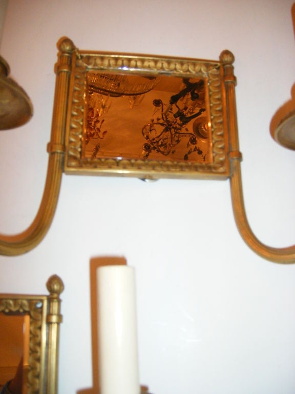 Pair of French neoclassic style circa 1920's gilt bronze two-light sconces with mirror back.

Measurements:
Height: 8