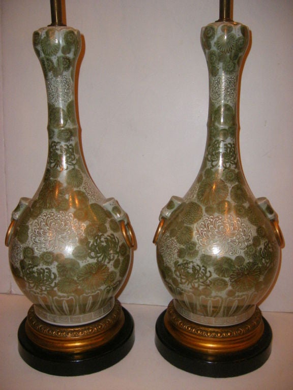 Paar große Tischlampen aus grünem Porzellan mit Blumendekor in weißen Tönen und vergoldeten Details. Vergoldete und ebonisierte Sockel.

Maße: 21
