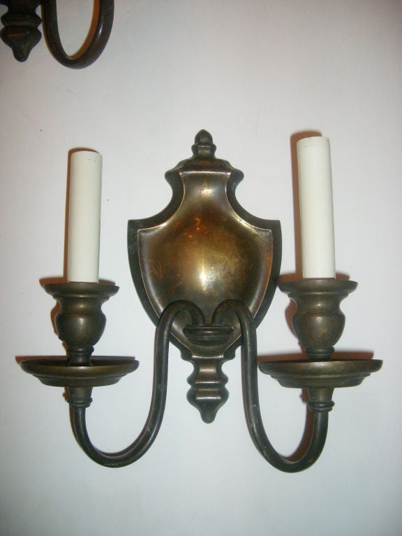 Pair of bronze circa 1920's two-arm Caldwell sconces with urn-shaped backplate and original patina. 

Measurements:
Height: 10