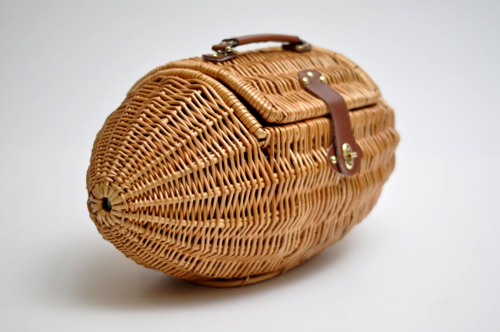 FUN WICKER PICNIC BASKET SHAPED LIKE A FOOTBALL CIRCA THE 1960S.  LINED INSIDE WITH FOOTBALL PRINTED FABRIC.