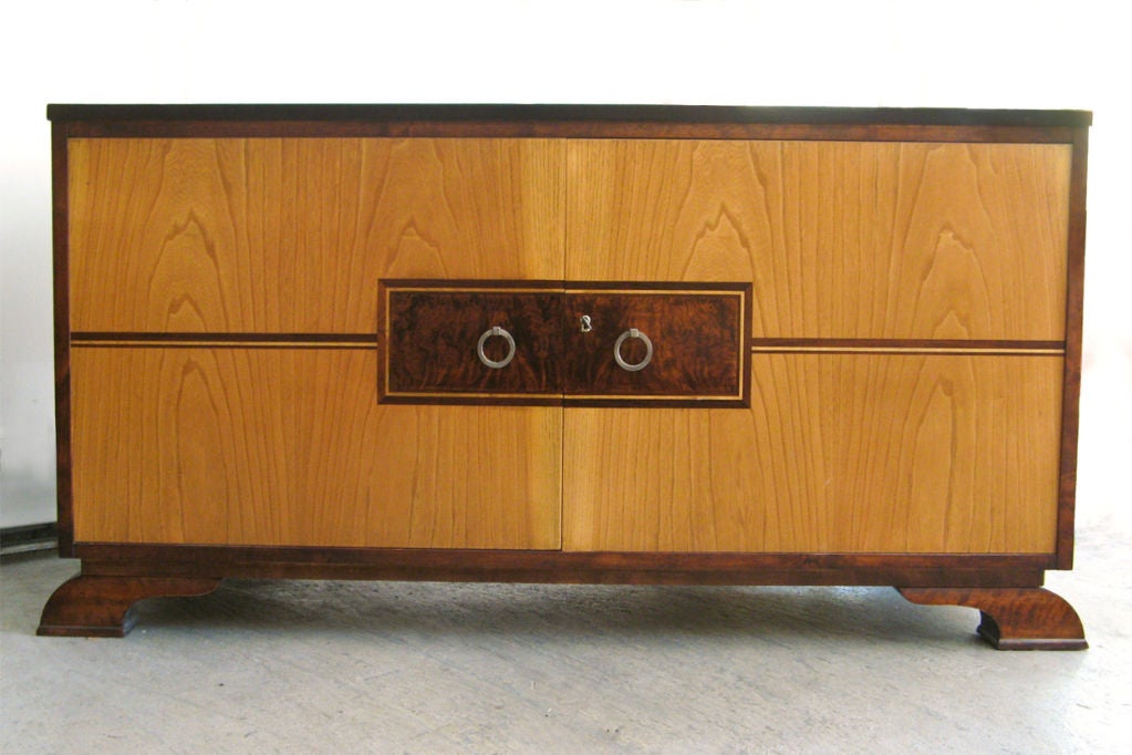 Sleek Swedish Art Deco 2-door cabinet / sideboard with elm, birch and burled wood veneers. Solid brass pull rings are silver plated. The cabinet offers shelves and two drawers and would be ideal for audio/video components. Beautifully restored in