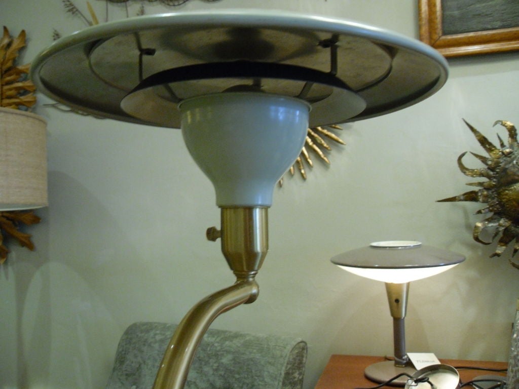 Classic flying saucer shaped standing lamp. Adjustable height and swivel curved brass arm with a cream enamel shade and base.