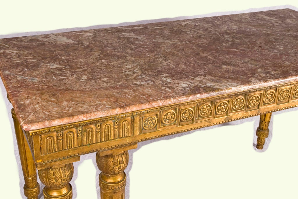 This mid-19th century French giltwood console table has beautiful carved wood details on all six of its legs. The contrast of the table's clean lines work particularly well with the marble top in lovely shades of peach colored marble. Perfect in a