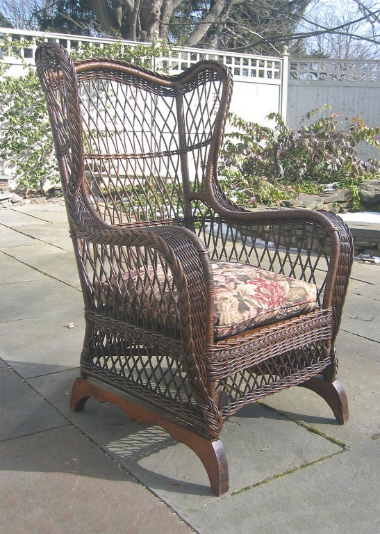 Grand scale Bar Harbor wicker wingback armchair in natural stained finish.  Heywood Wakefield label.  Comfortably deep-seated with a high arched crest, broad wing span and curved wide flat arms tapering to a point at the foot.  The chair is