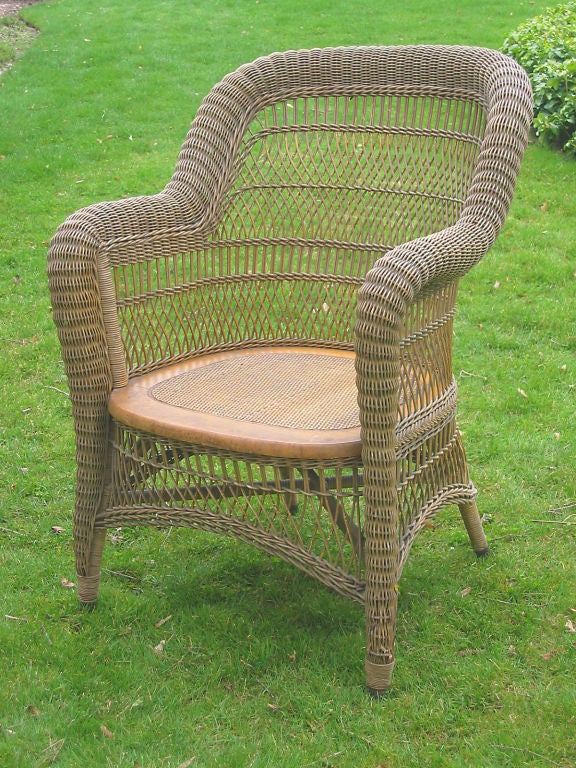 Victorian wicker armchair in natural stained finish. Classic rounded back form with serpentine roll from crest to arms with continuous taper to brass capped feet. Gently arched skirts. Closely woven pressed cane seat.