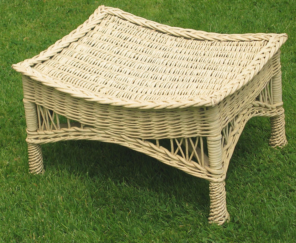 Traditional Bar Harbor style wicker ottoman in old bone colored paint. Rectangular concave woven platform with braided border. Full arched skirting leading to pineapple twist-wrapped feet. Last photo shown with companion armchair listed & priced