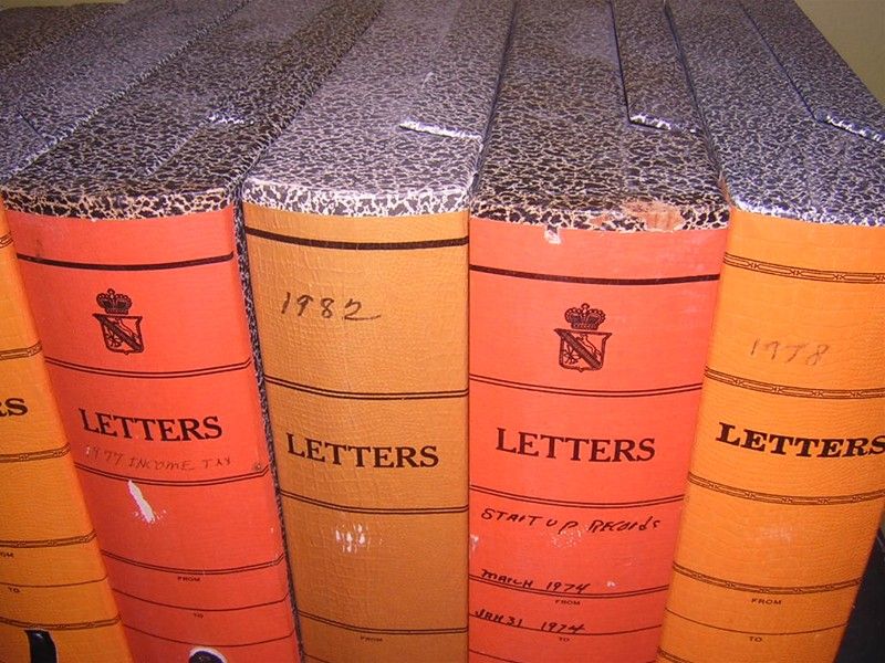 Set of nine vintage, hardboard letter boxes with clasps and A-Z dividers inside used as organizational files. Lush orange color along spine with worn leather tabs and classic, schoolbook black-and-white on sides and top edge. Store magazines or