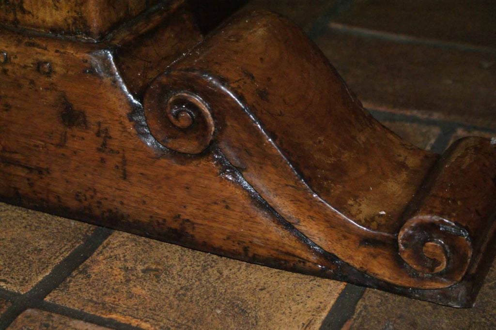 Italian Renaissance Style Scroll Base solid walnut table.  Deep rich polished patina.  The top is 3 inches thick, pegged and mitred with a single center panel, moulded edge.  The base is  a beautifully carved scroll  trestle with two turned 