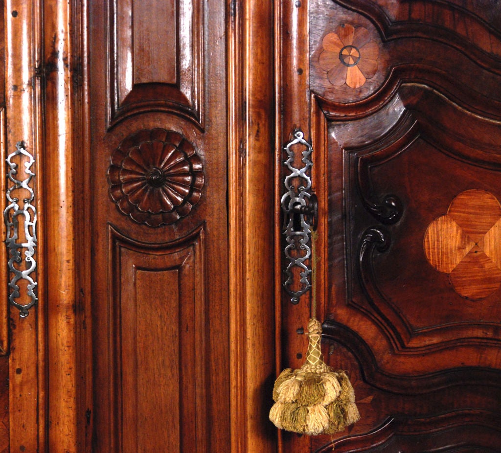 The molded cornice above two raised paneled doors, opening to a shelved interior with two small drawers; above a carved frieze all resting on cabriole leg feet.