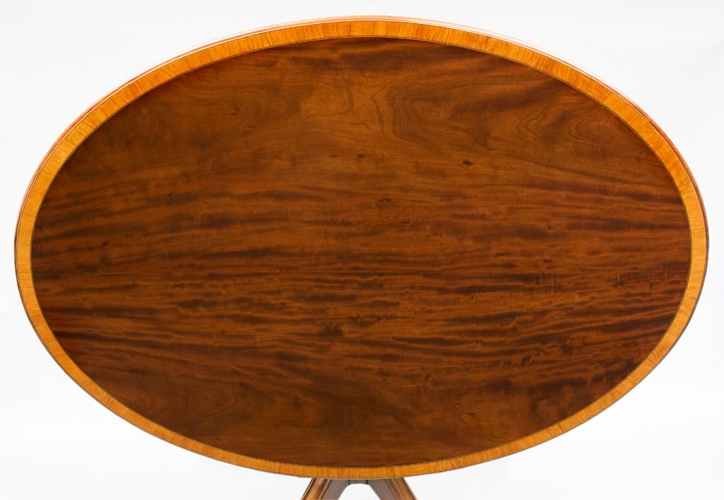 Superb Georgian mahogany oval tilt-top breakfast or centre table with satinwood banding on four beautifully proportioned molded splay legs, ring turned pedestal base with brass casters. Underside with label from 