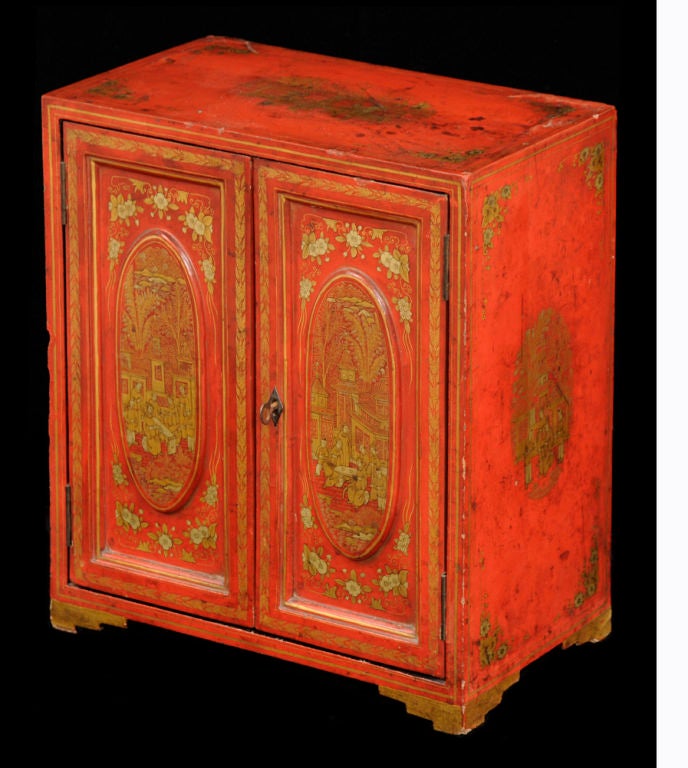 Chinese export miniature red lacquered table top cabinet with gilded decoration of figure having tea, pogodas, trees and flowers. The two doors open to reveal five interior drawers with brass knobs.