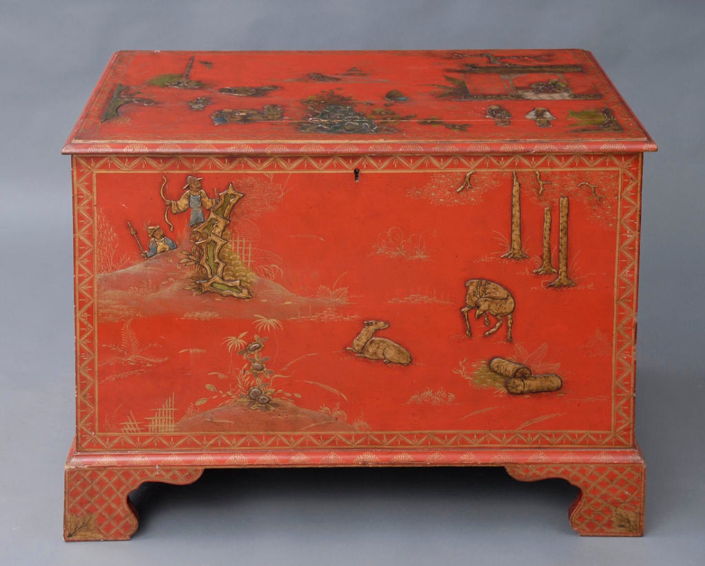 Chinoiserie red lacquered and gilded pine chest with hinged lift top enclosing a black painted interior with sliding tray, on shaped bracket feet.  Top and sides decorated with household scenes, animals and floral designs.