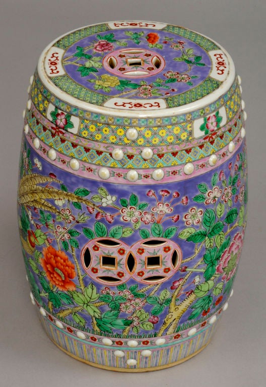 Chinese porcelain garden seat, pierced with cash coins, enamel decorated with birds of paradise, peonies, prunus blossoms in wonderful colors of lavenders, greens, pinks, yellows, all set within geometric borders.