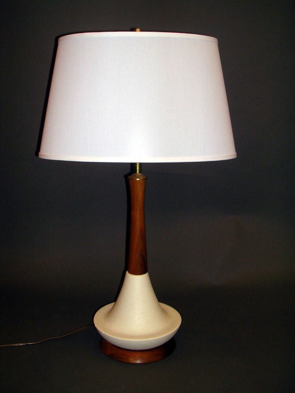 A pair of Mid Century modern Danish table lamps with cylindrical flaired teak neck ending in a textured white ceramic conical body on a teak domed base rewired with a three-way switch and new textured fabric off white lamp shades.