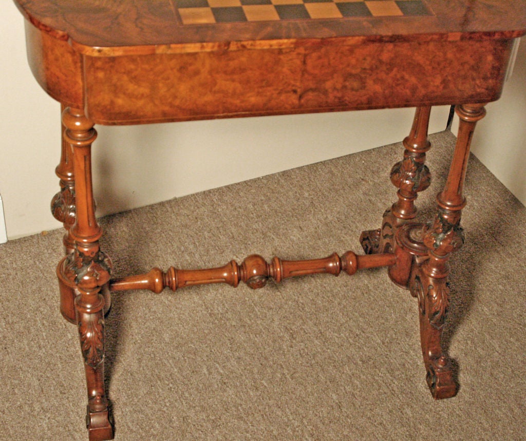 Beautiful Burl Walnut English Victorian Chess/Occasional table.<br />
Detailed acanthus style carvings with stretcher and brass rosettes.   Drawer with brass knobs.   Exceptional condition and patina.   Satinwood and Mahogany chess section on top.