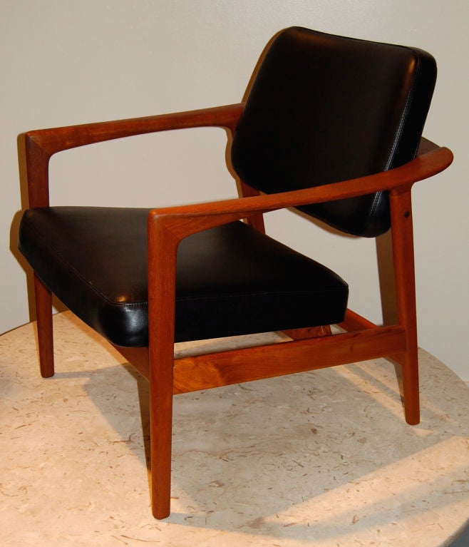 Handsome armchair designed by Folke Ohlsson for Dux, graceful organic lines created out of solid teak. The seats are warpped in newly upholstered leather and seem to float off the frame. Nice little detail with the brass spacers on the bottom of the