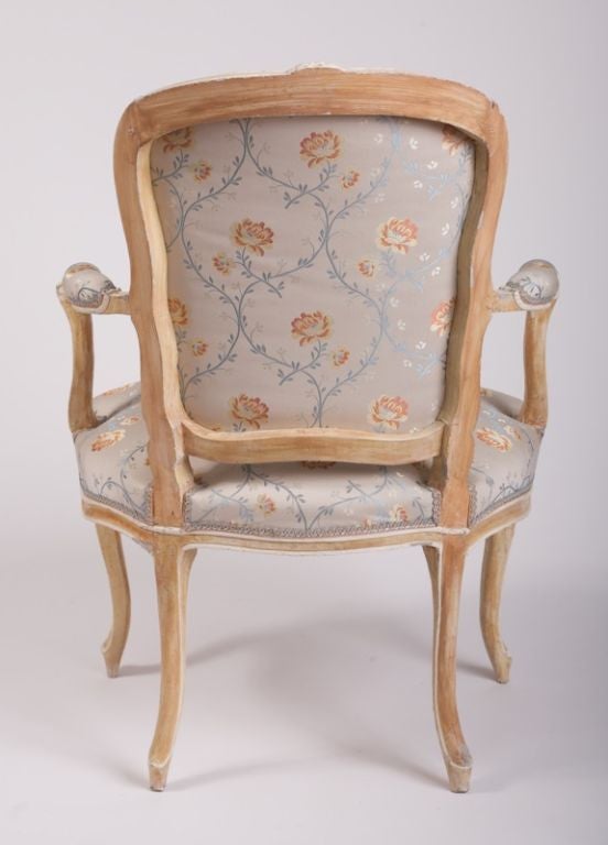 With a cartouche-shaped backrest, the top rail carved with flowerheads and leaf tips, out-scrolled padded armrests on molded voluted supports, the almost circular seat carved to match the backrest, raised on cabriole legs ending in scrolled toes. 