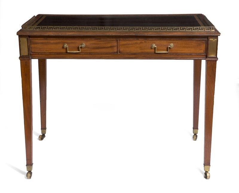 In the French taste‚ the rectangular tooled leather inset writing surface with a three-quarter gallery‚ above two frieze drawers‚ with sham drawers to the reverse‚ raised on square tapering legs ending in casters.