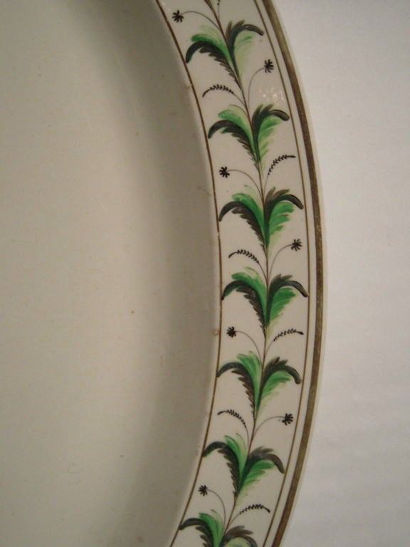 An oval Staffordshire platter decorated with hand-painted feather and star ornament in shades of apple and forest green and brown, with brown stripe along the perimeter, circa 1810.