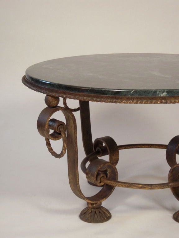 A stylish French gilt iron and green marble top circular coffee table in the manner of Gilbert Poillerat.