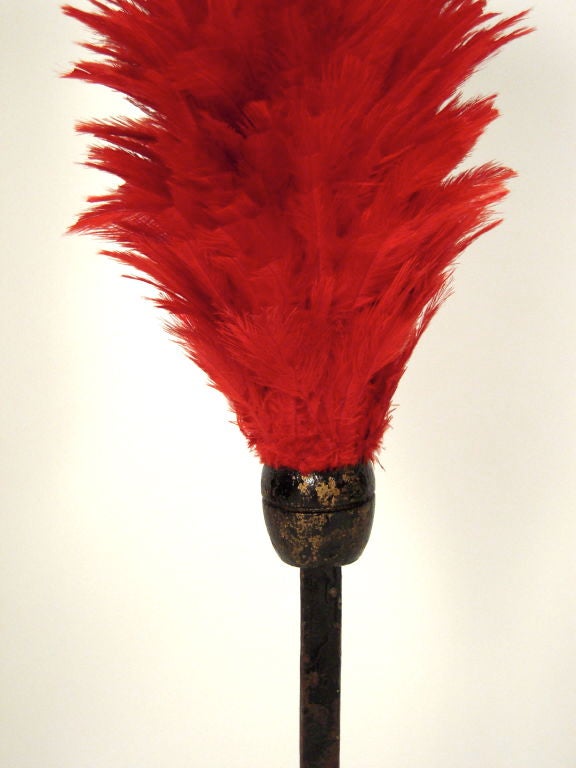 A  19th century cherry red feather parade or circus  feather decoration for a horse, c. 1880s, on its original flattened iron rod, mounted on an old wood  foundry pattern mold.