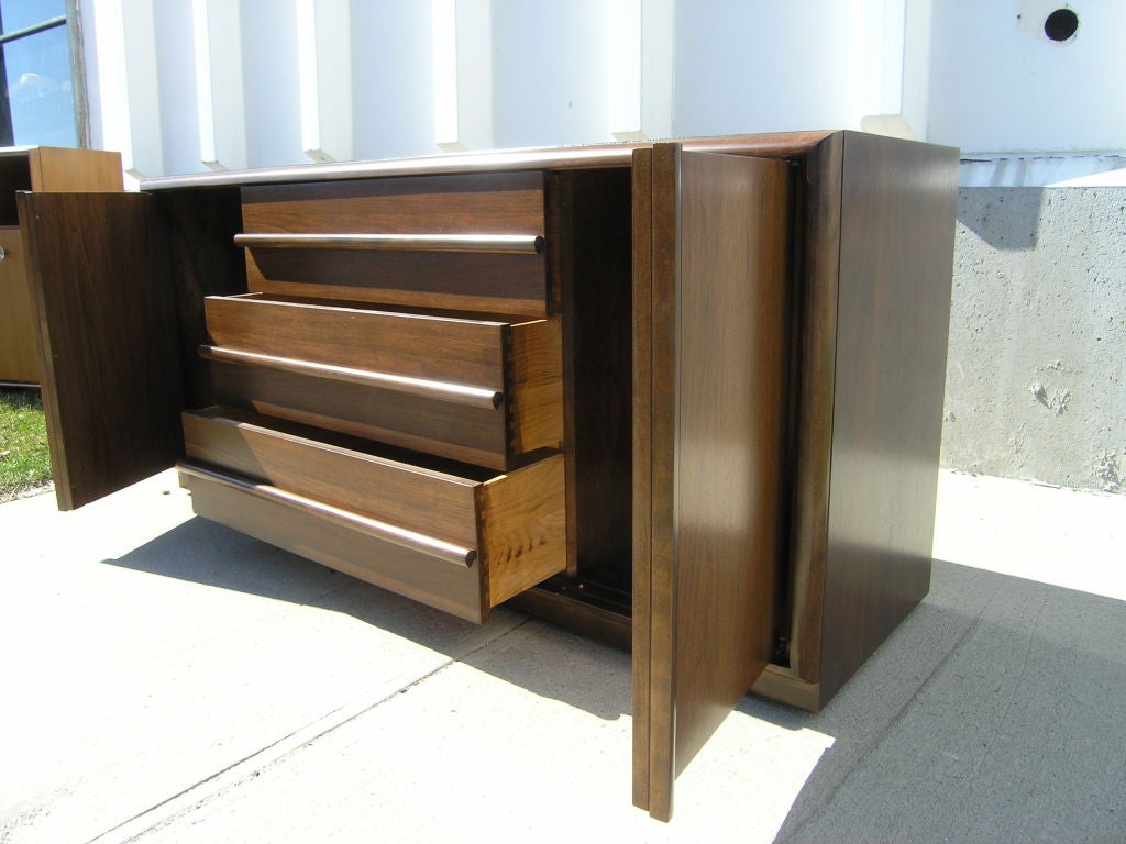 T.H. Robsjohn-Gibbings entwarf diesen hübschen Mahagonischrank für die Widdicomb Furniture Company. Das solide gebaute Gehäuse hat in der Mitte drei geräumige Schubladen mit geradlinigen Holzgriffen und zusätzliche Fächer hinter Türen auf beiden