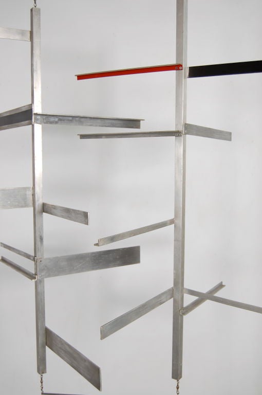 Derek Carruthers (b 1935); an Interfusions mobile constructed in aluminium and consisting of two rotating vertical bars to which are attached 17 horizontal arms , two are painted black on one side and one red . The two sides are designed to rotate