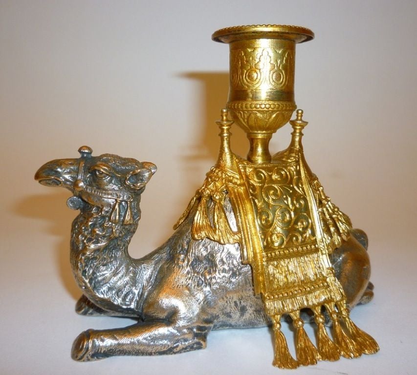 Pair of Continental Silvered & Gilt Bronze Camel Candlesticks - probably Austrian c.1900<br />
<br />
Each in the form of a recumbent dromedary camel with gilt bronze Arabian style camel saddle, adorned with tassels and foliate decoration.