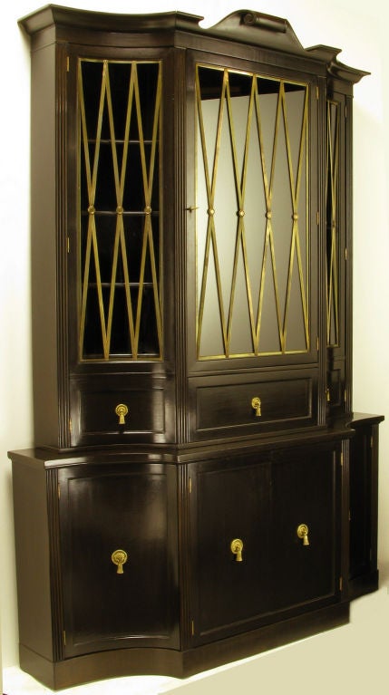 Elegantly detailed, with brass grill work over the curved glass side doors and flat center door of the upper cabinet.  Grosfeld House tall cabinet/sideboard/buffet has been recently restored in dark walnut. The bottom cabinet has curved side doors