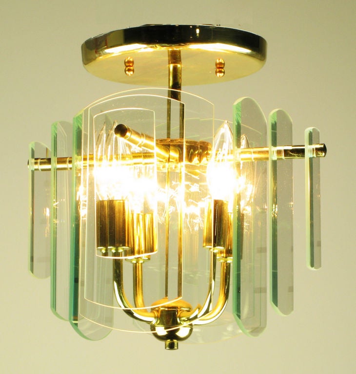 A pair of brass four arm ceiling lights with four sides of graduated and beveled glass. Each side features three layers of glass plates that step down in size from the center.   One of five pairs available.