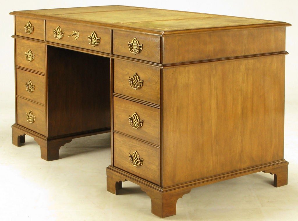 From Baker's fine Collector's Edition, this Georgian style double pedestal desk features elaborately cast brass pulls and escutcheons. Three-panel tooled saffron yellow leather top is patinated. Walnut case is antiqued to resemble an 18th century