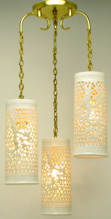Beautifully pierced ceramic blanc de chine ceiling fixture with three cylindrical pendants. Porcelain fretwork incorporates lovely Ming tree design. Brass canopy, chain, and curved arms in very good original condition.