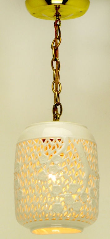 Blanc de chine and brass reticulated single pendant light. Beautifully made porcelain shade with branches and foliate detailing hanging from a brass chain and canopy. Single bulb illumination.