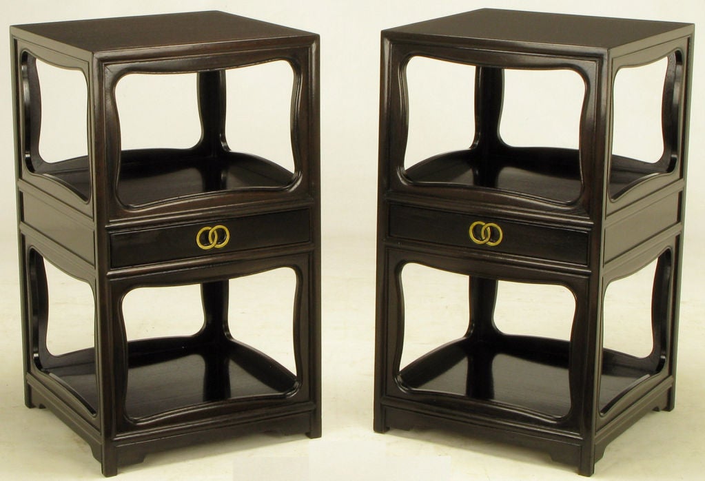 Pair night stands by Michael Taylor for Baker Furniture.  Dark stained walnut with a single drawer. Signature interlocking gilt rings pull carved into the solid wood drawer fronts. Open top and bottom compartments are framed with a scalloped edge on