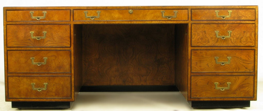 Beautiful burled walnut wood and black lacquered plinth base executive desk, from the Wellington Group, by the John Widdicomb Company. Brass recessed pulls, lower file-sized drawers, and front pull out writing plateau. From the Chicago office of a