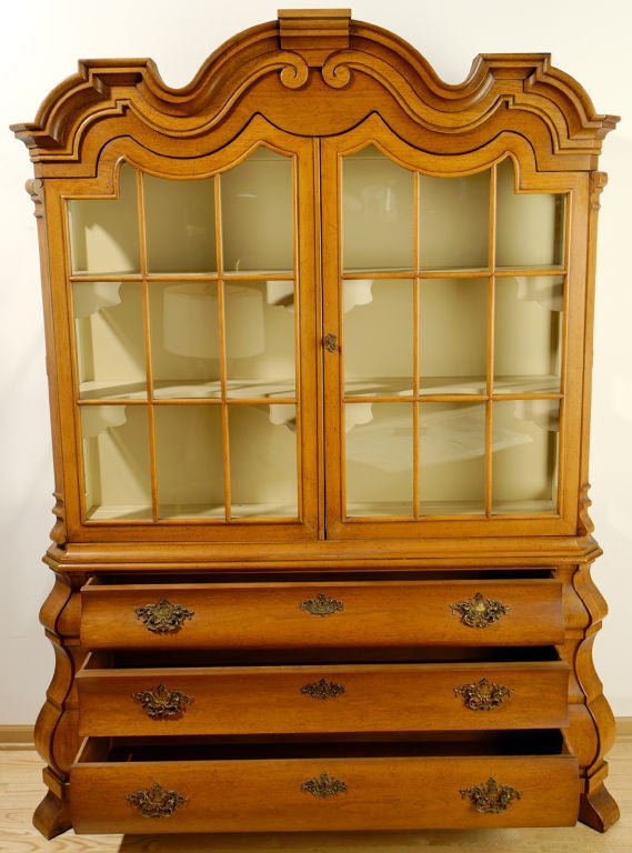 This impressive cabinet is from Draper's 1963 Viennese Collection for Henredon. It features a bombe base with three drawers, splayed feet, and intricately chased brass drop pulls. <br />
<br />
Above the base is a vitrine section with two arched