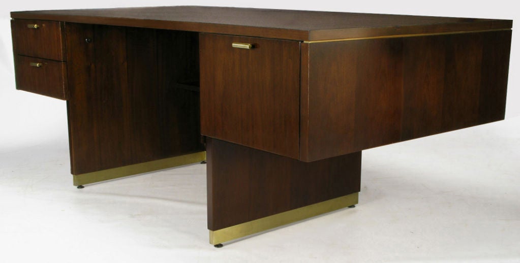 Very fine and unusual executive desk by venerable American desk manufacturer, Myrtle Desk Co. Walnut body is on an open pedestal base, with a recessed shelf, and brass inlay. The three drawers have pulls that are solid brass halved bars, with nice
