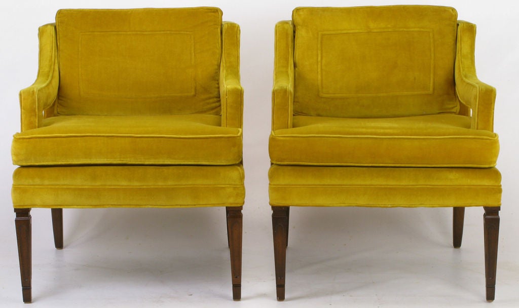 Saffron velvet upholstered club chairs with loose seat cushions.  Trapunto detailed loose back cushions, with fully upholstered open arms.  Carved walnut wood upside down obelisk front legs and carved wood saber shaped back legs. <br />
<br