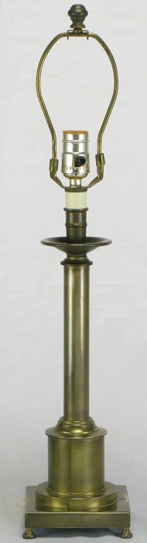 Brass regency style candle stick table lamp with an aged finish. Heavy and evocative of the designs by Stiffel, the stepped plinth base is uniquely footed. Sold sans shade.