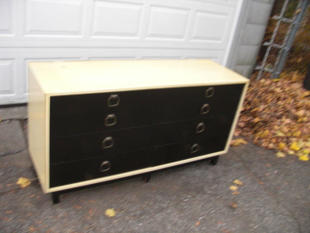A two-tone ( cream and black) lacquered 8-drawer credenza / long dresser with graduated drawers and nickel hardware. We have the original [ all glass ] mirror that went above this chest. It is priced $ 500 . We also have a matching headboard from