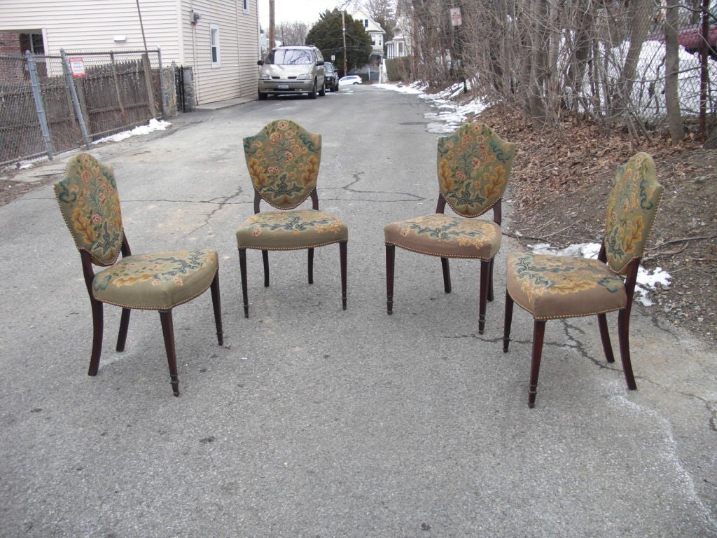 A set of 4 Sheraton style shield back chairs with wonderful original hand made gros and petit point upholstery. Sold to us as English and 19th century however I think circa 1910 is more likely.The petit point seems to be silk.