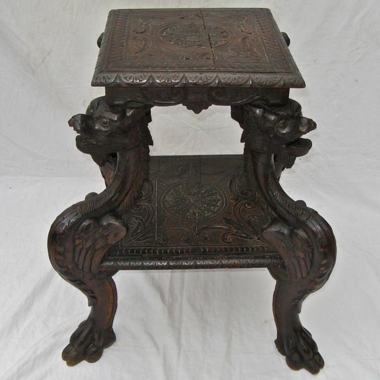 Ornate Italian carved dragons & scrolls, which were typical florentine design, can be seen in this two tiered occasional table which stands on four animal claw feet.  The intricate design work on the table tops depict scrolls, acanthus leaves, and a