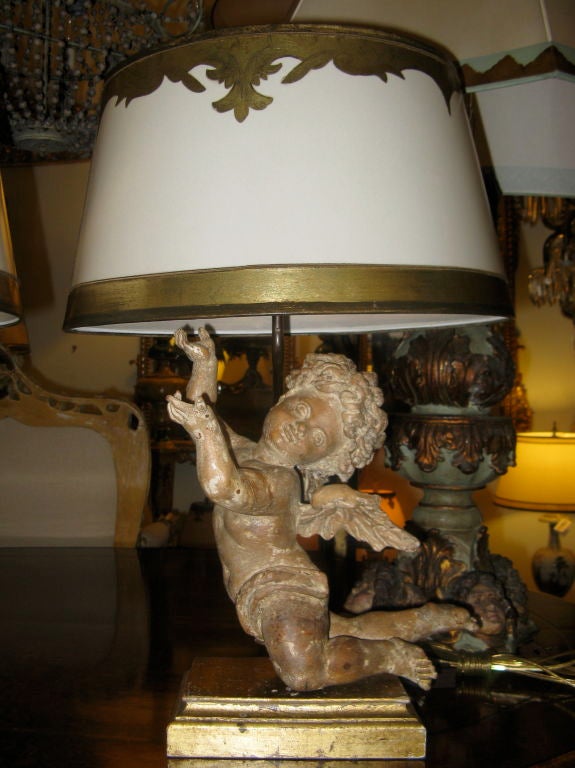 Pair of carved wood cherubs placed on giltwood bases and French mounted into lamps with custom painted parchment shades.