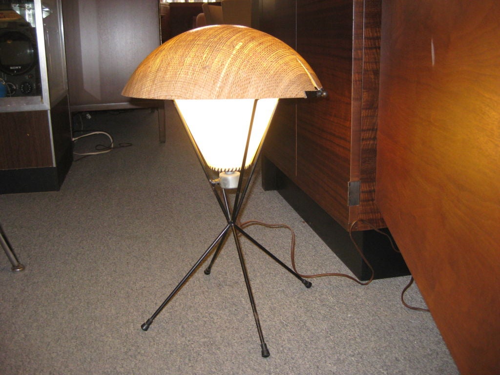 Wrought iron and fiberglass table lamp on tripod base.  Sectioned fiberglass shade splits and pivots to provide infinite number of possible positions.  Single light bulb is covered with additional fiberglass shade.