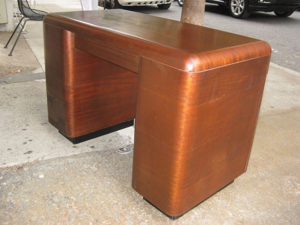 Totally original double pedestal bent plywood desk with unusual curved drawers and top with corners similar to the Eames leg splints. Opening between banks of drawers is 21 inches.