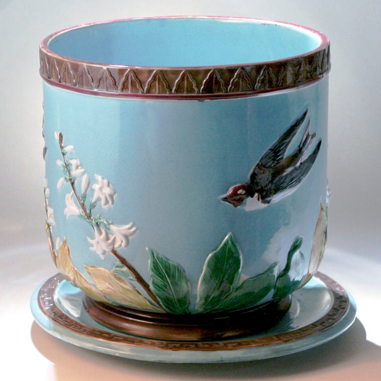 Grande jardinière o fioriera in maiolica con uccello nero volante e fiore di orchidea bianco su fondo turchese. Il sottopiatto abbinato ha un bordo con motivo a chiave. Attribuito a: Holdcroft.