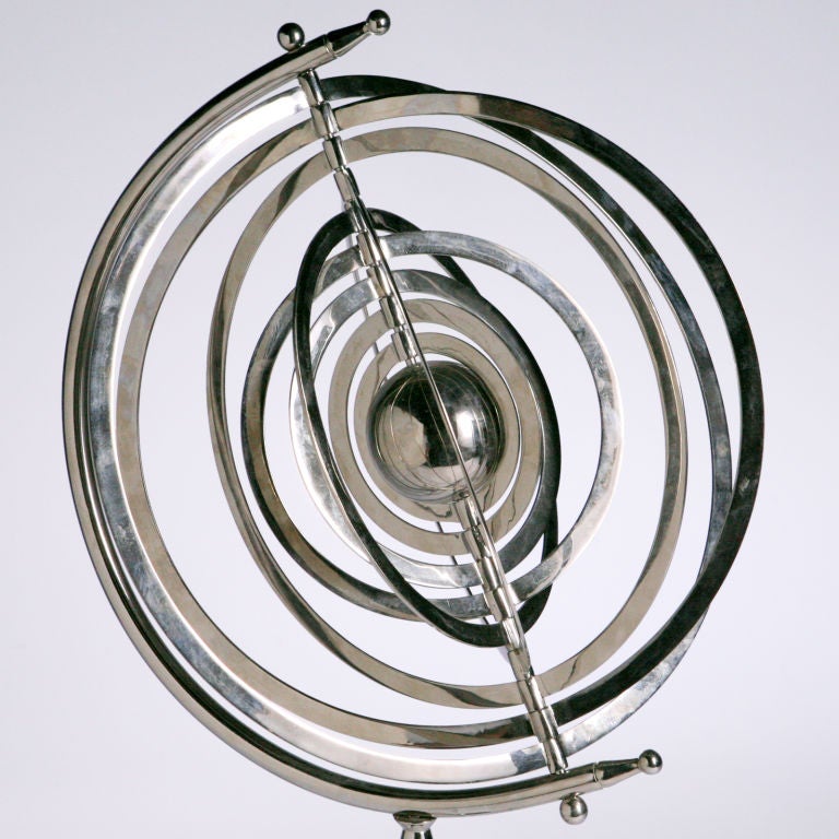 Vintage polished metal armillary on stand.  This old astronomical instrument has center ball circled by nine concentric bands within a half-moon support frame.  The bands represent the varying positions of the celestial bodies.