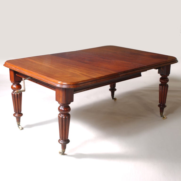 Mahogany dining table with Regency-style reed legs on casters. Handle extends table for extra leaves. Closed: 29.5