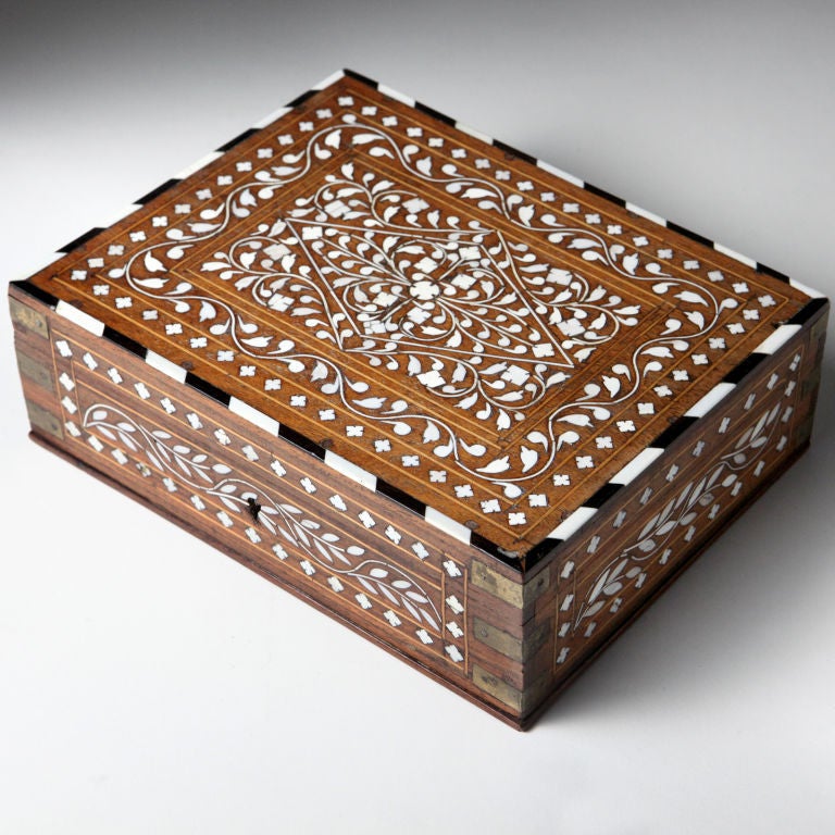 Antique Syrian box with an intricate bone inlay mosaic.  Designed with a center flower medallion framed by a swirling vine and diamond shaped pattern.   The top border with ebony and bone.  The corners with inlaid brass strap mounts.