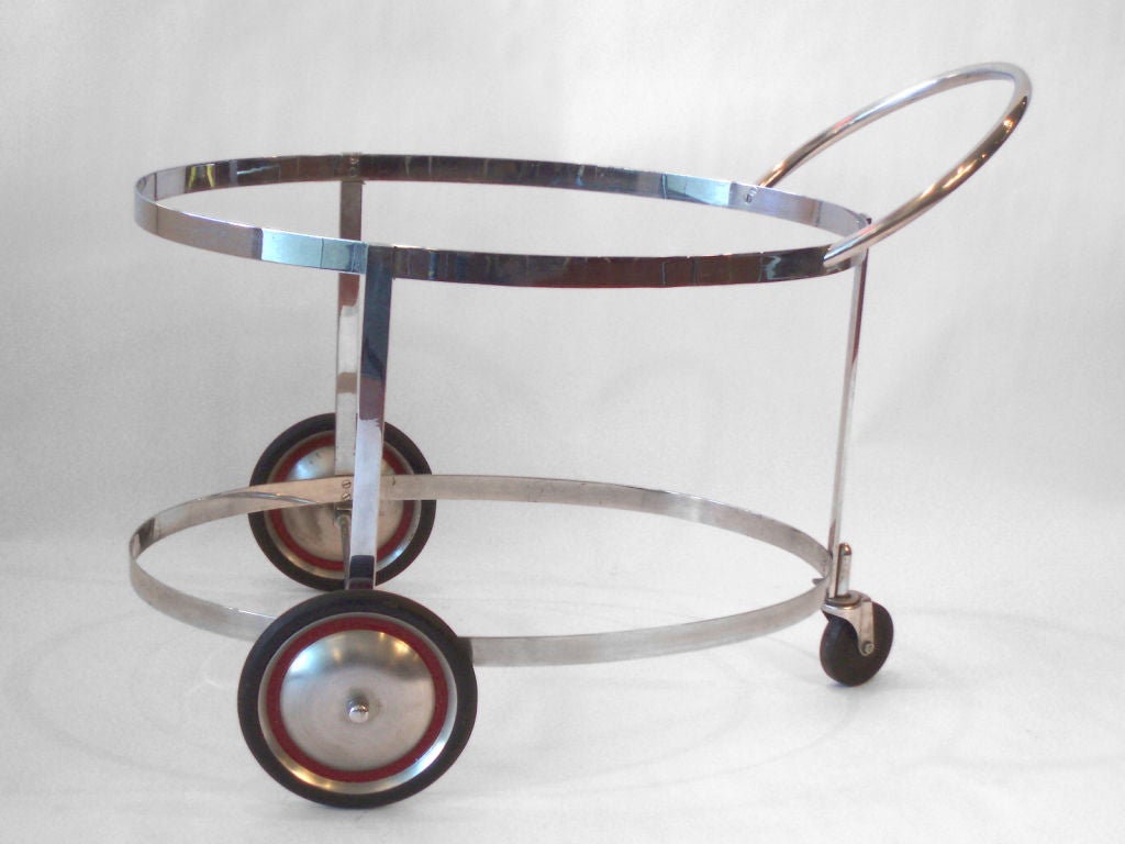 Moderne chrome drinks cart  of the period and in the style of Gilbert Rohde for Troy Sunshade.
Two oval tiers holding glass shelves on chrome plated frame . Trolley wheels on back end single caster on front . very nice condition . 